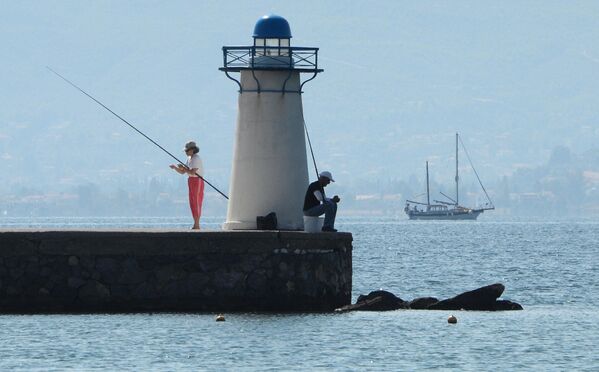 Отдыхающие ловят рыбу возле маяка в заливе Нотиос-Эввоикос Эгейского моря