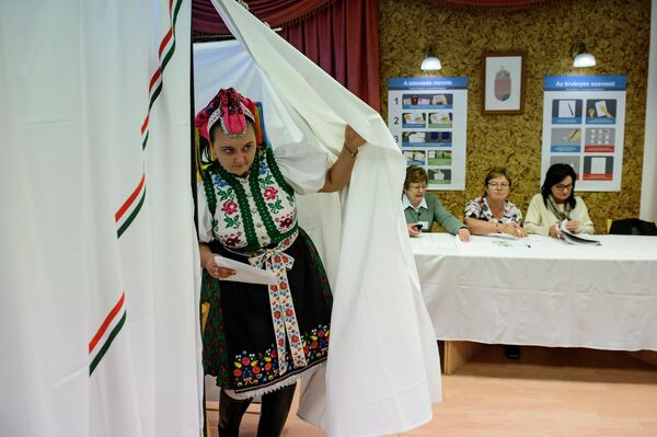 Женщина в традиционной одежде выходит из кабины для голосования, Венгрия.