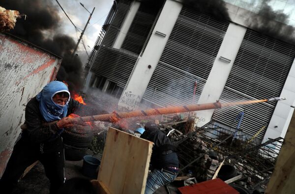 Демонстрант стреляет из самодельного оружия во время акции протеста в Кито, Эквадор