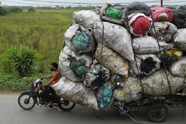 Сборщик мусора везет пластик на переработку в пригороде Ханоя
