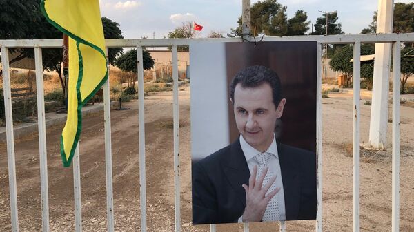 Портрет президента Сирии Башара Асада на фоне флага Турции и курдских сил самообороны (YPG) на КПП на сирийско-турецкой границе в городе Кобани