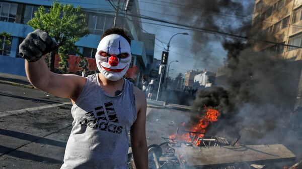 Демонстрант  на горящих баррикадах во время акций протеста в Чили