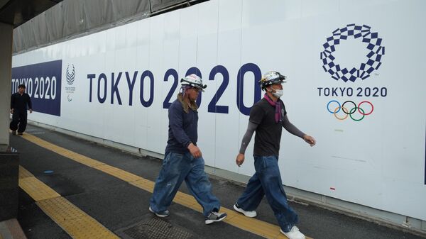 Работники проходят мимо логотипа Олимпийских игр-2020 в Токио