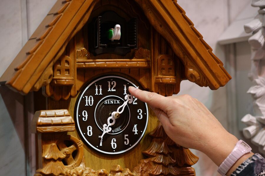 Продавщица демонстрирует настенные часы в магазине Время в Новосибирске