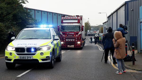 Полиция сопровождает грузовик, в котором были обнаружены телами, в британском городе Грейс