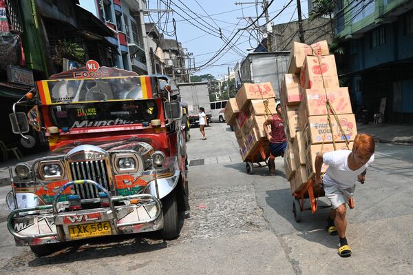 Рабочие с тележками на улице в китайском квартале Манилы