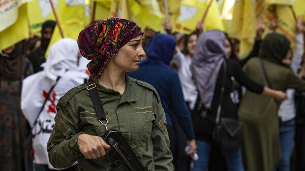 Сотрудница курдской службы внутренней безопасности на страже во время демонстрации в Сирии