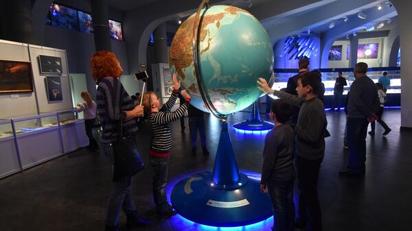 Посетители у глобуса Земли в музее Урании Московского планетария