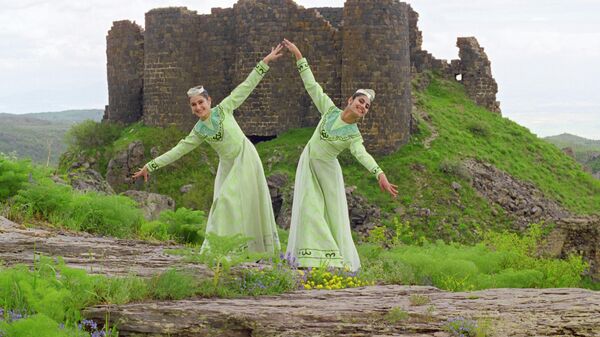 Танец у стен крепости Амберд - исторического комплекса, из замка и церкви, на склоне горы Арагац в Армении