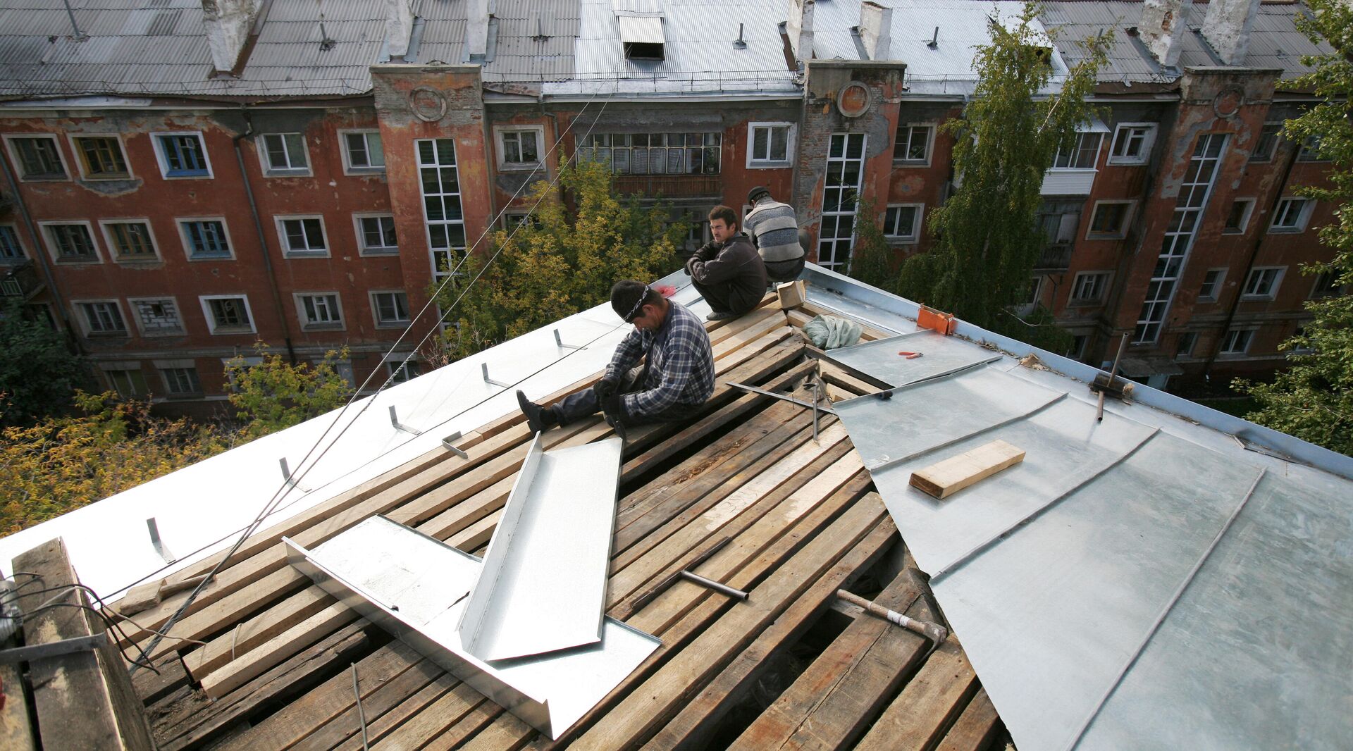 Рабочие перекрывают крышу многоэтажного дома - РИА Новости, 1920, 22.03.2022