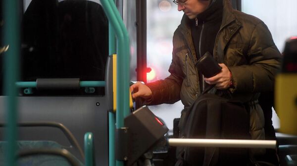 Пассажир прикладывает билет к валидатору в автобусе