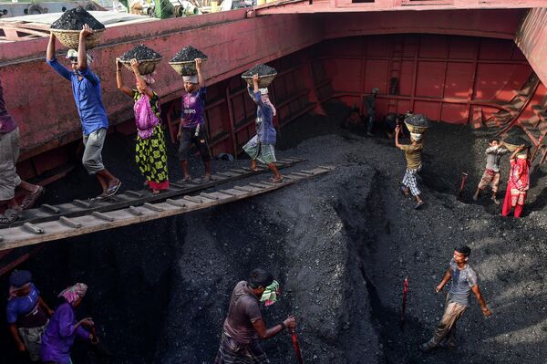 Рабочие выгружают уголь с грузового корабля в Габтоли, Бангладеш