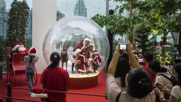 Семья в костюмах Санта-Клауса позирует внутри рождественского украшения в торговом центре в Бангкоке