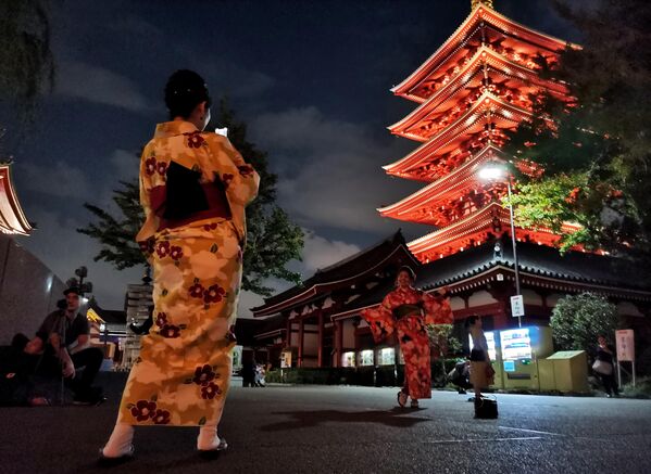 Девушки фотографируются на фоне Буддистского храма Асакуса Каннон в Токио