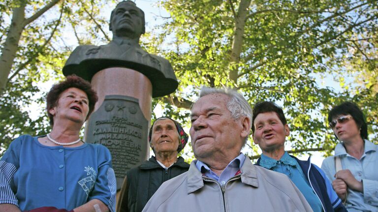 Михаил Калашников на родине в селе Курья Алтайского края с односельчанами на фоне своего бюста