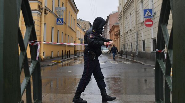 Сотрудник правоохранительных органов огораживает территорию на время следственных действий в Санкт-Петербурге