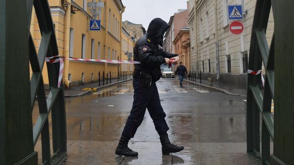 Сотрудник правоохранительных органов огораживает территорию на время следственных действий в Санкт-Петербурге