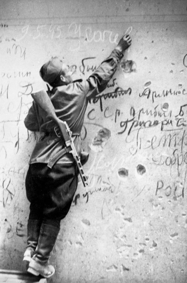 Советский боец Егор Усачев делает памятную надпись на стене Рейхстага.