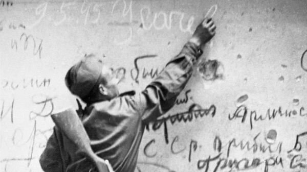 Советский боец Егор Усачев делает памятную надпись на стене Рейхстага.