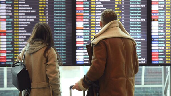 Пассажиры смотрят информационное табло в аэропорту 