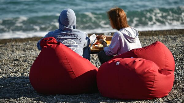 Молодые люди обедают на берегу моря