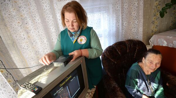 Волонтер помогает ветерану Великой Отечественной войны настроить прием цифрового телевидения
