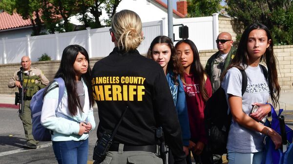Учащиеся эвакуируются под руководством сотрудника департамента шерифа после стрельбы в Saugus High School, штат Калифорния. 14 ноября 2019 