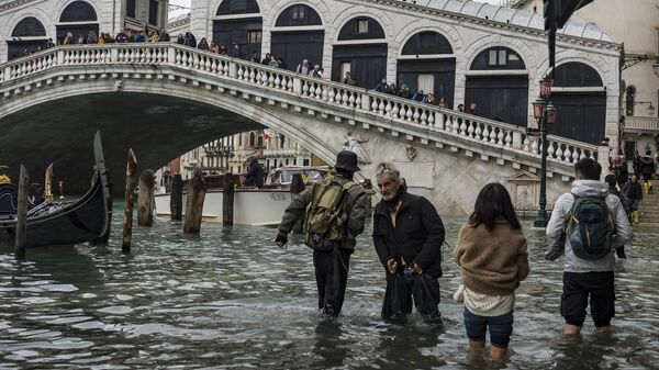 Прохожие у моста Риальто в Венеции во время наводнения