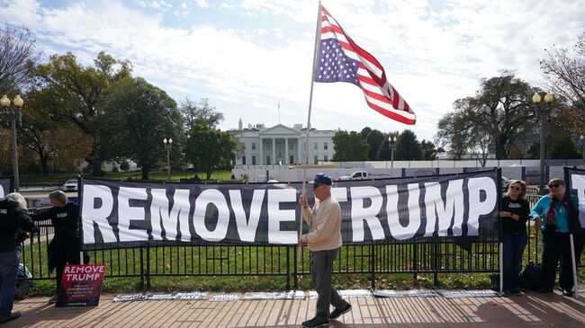 Активисты держат плакат с просьбой об импичменте президента США Дональда Трампа