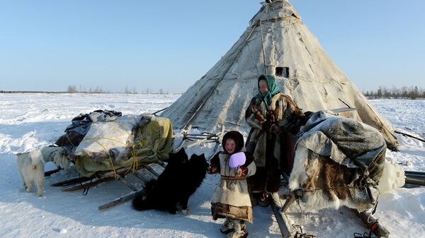 Женщина с ребенком у чума в стойбище в Надымском районе Ямало-Ненецкого автономного округа