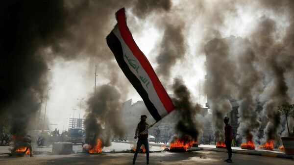 Протестующий размахивает флагом Ирака во время антиправительственной акции в Ан-Наджафе