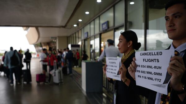 Сотрудники авиакомпании держат таблички с номерами отмененных рейсов в аэропорту Манилы, Филиппины. 3 декабря 2019