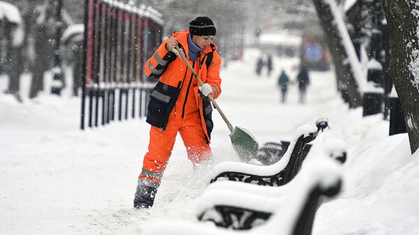 Сотрудница коммунальных служб убирает снег