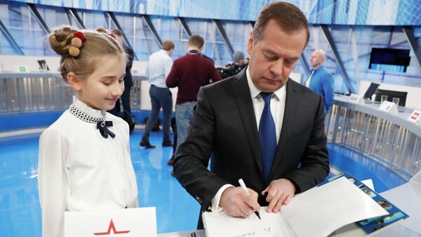 Председатель правительства РФ Дмитрий Медведев оставляет автограф в книге для ведущей канала Карусель Ани Тадыщенко после интервью российским телеканалам