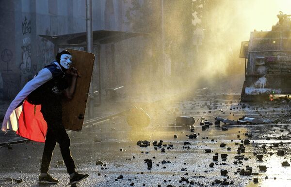 Демонстрант в маске Гая Фокса во время протестов против правительства в Сантьяго