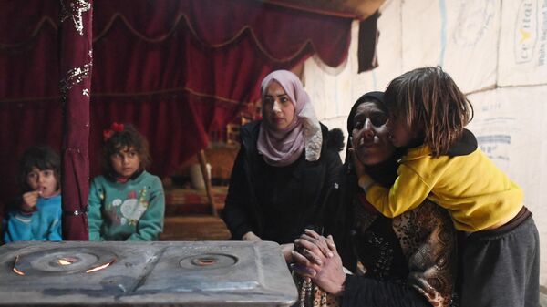 Женщины с детьми, живущие в палаточном городке в Сирии