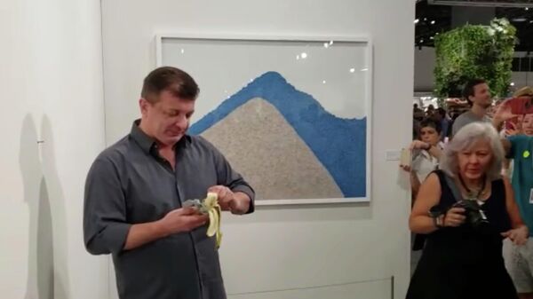 Художник Дэвид Датуна ест работу Маурицио Каттелана на выставке Арт-Базель