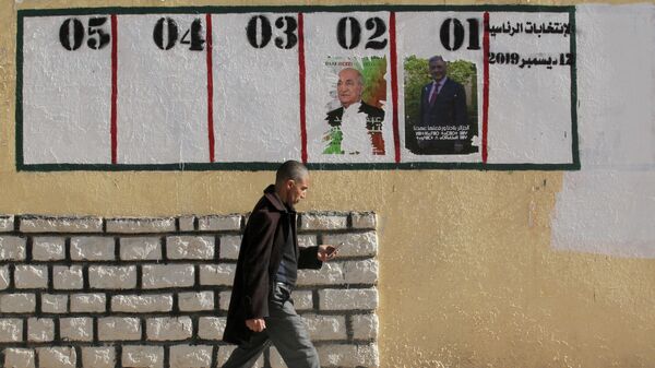 Мужчина проходит мимо предвыборных плакатов в Айн-Усера, Алжир