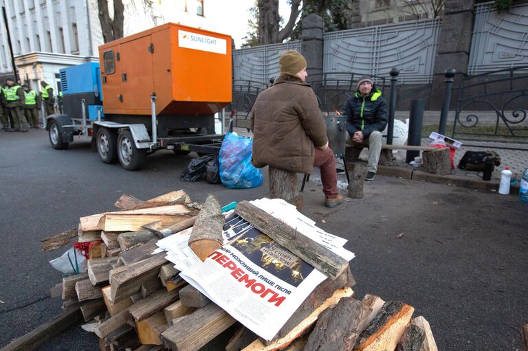 Участники акции протеста греются у открытого огня возле здания администрации президента Украины в Киеве Участники акции протеста греются у открытого огня возле здания администрации президента Украины в Киеве