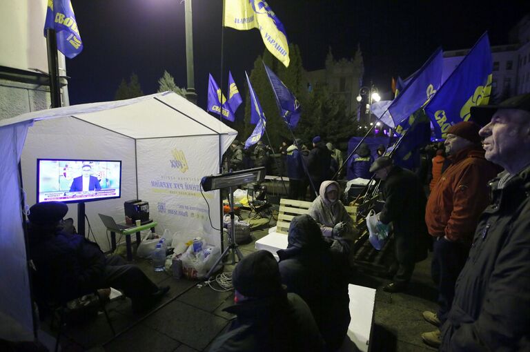 Участники акции протеста смотрят трансляцию новостей возле здания администрации президента Украины в Киеве Участники акции протеста смотрят трансляцию новостей возле здания администрации президента Украины в Киеве