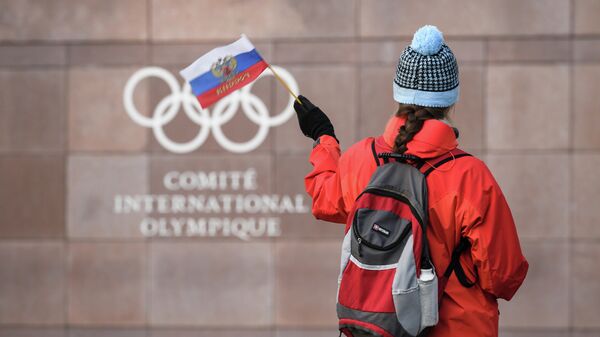 Болельщица с российским флагом на фоне штаб-квартиры Международного олимпийского комитета (МОК) в Лозанне (Швейцария)