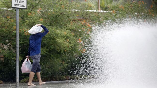 A man shields himself with a bag as he walks along a flooded street in the Qatari capital Doha, during heavy rainfall, on October 20, 2018. (Photo by STRINGER / AFP)