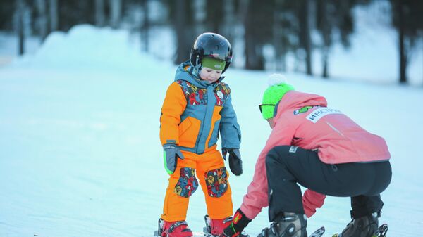 Инструктор учит ребенка кататься на горных лыжах в ГЛК Манжерок