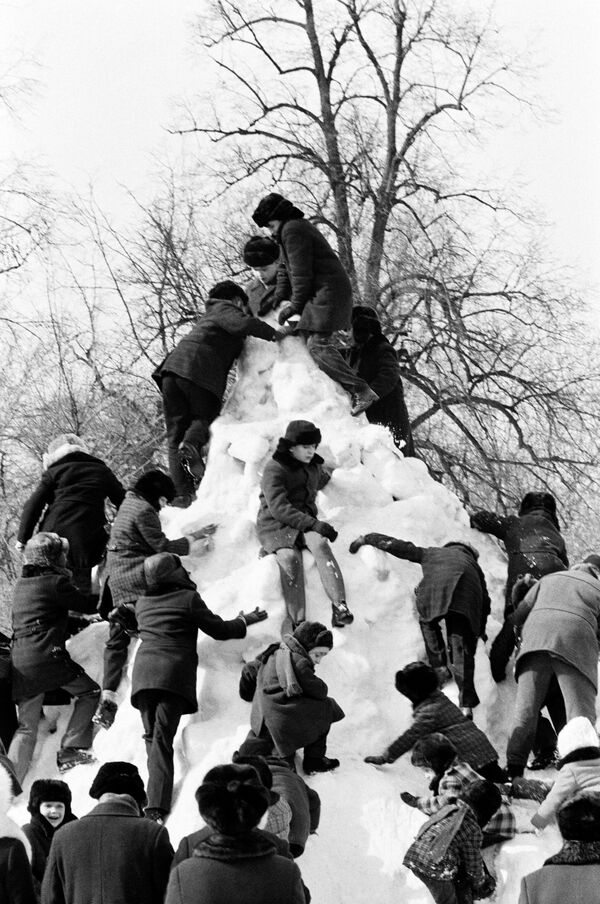 Детвора взбирается на снежную горку во время праздника Проводы русской зимы