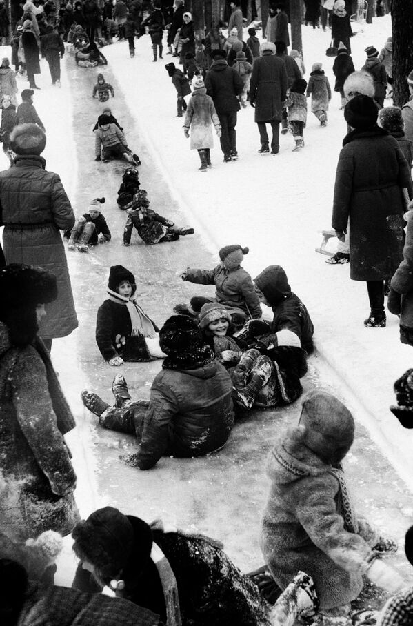 Дети катаются с ледяной горки на празднике Проводы русской зимы