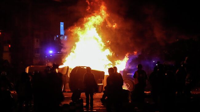 Protesters stand around a burning barricade made with garbage containers during a protest called by Catalan separatist movement Democratic Tsunami outside the Camp Nou stadium in Barcelona on December 18, 2019, during the El Clasico Spanish League football match between Barcelona FC and Real Madrid CF. - Twelve people were injured as police charged hundreds of masked protesters who set garbage bins on fire near Barcelona's Camp Nou stadium, as Barcelona and Real Madrid faced off in the first Clasico of the season, according to emergency services. (Photo by Pau Barrena / AFP)