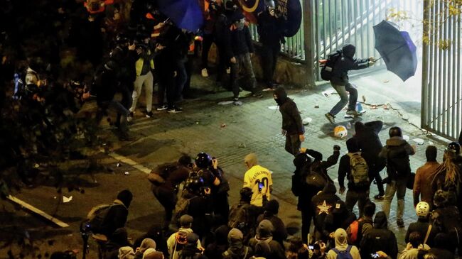 A protester with an umbrella tries to enter the Camp Nou stadium during a protest called by Catalan separatist movement Democratic Tsunami outside the stadium in Barcelona on December 18, 2019, during the El Clasico Spanish League football match between Barcelona FC and Real Madrid CF. - Twelve people were injured as police charged hundreds of masked protesters who set garbage bins on fire near Barcelona's Camp Nou stadium, as Barcelona and Real Madrid faced off in the first Clasico of the season, according to emergency services. (Photo by Pau Barrena / AFP)