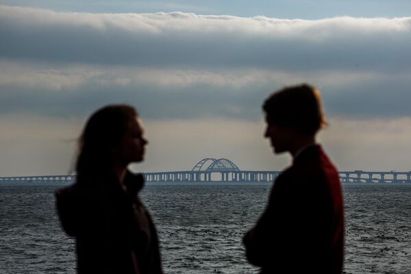 Молодые люди стоят напротив Крымского моста
