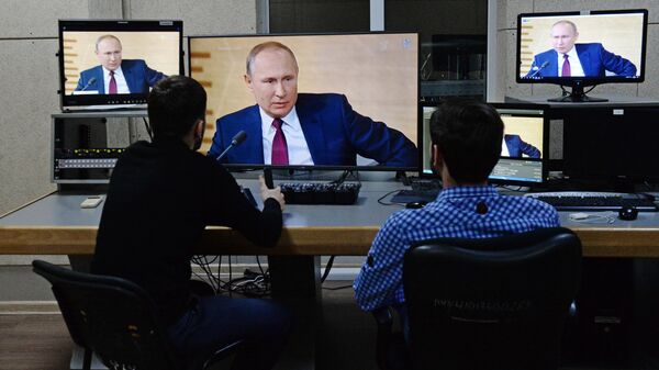 Сотрудники телеканала Грозный смотрят трансляцию пресс-конференции президента РФ Владимира Путина