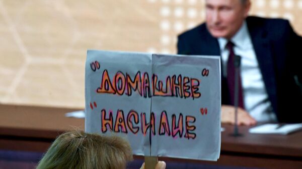 Журналист с плакатом Домашнее насилие во время большой ежегодной пресс-конференции президента РФ Владимира Путина 